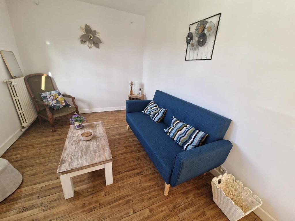 a living room with a blue couch and a table at Maison de ville proche de tous les commerces in Égletons