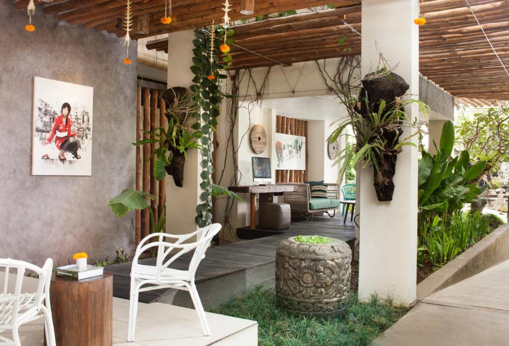 a patio with white chairs and a table at Grandmas Plus Hotel Seminyak in Seminyak