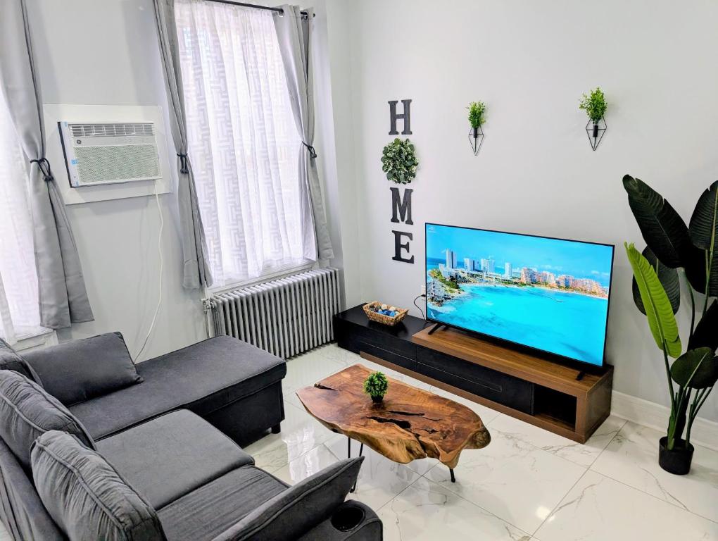 a living room with a tv and a couch and a table at Newly Renovated 2B 2BA apt! mins to PATH & NY! in Jersey City