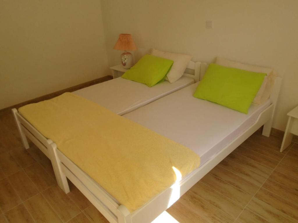 2 Betten in einem Zimmer mit grünen Kissen darauf in der Unterkunft Apartments Kanli Kula in Herceg-Novi
