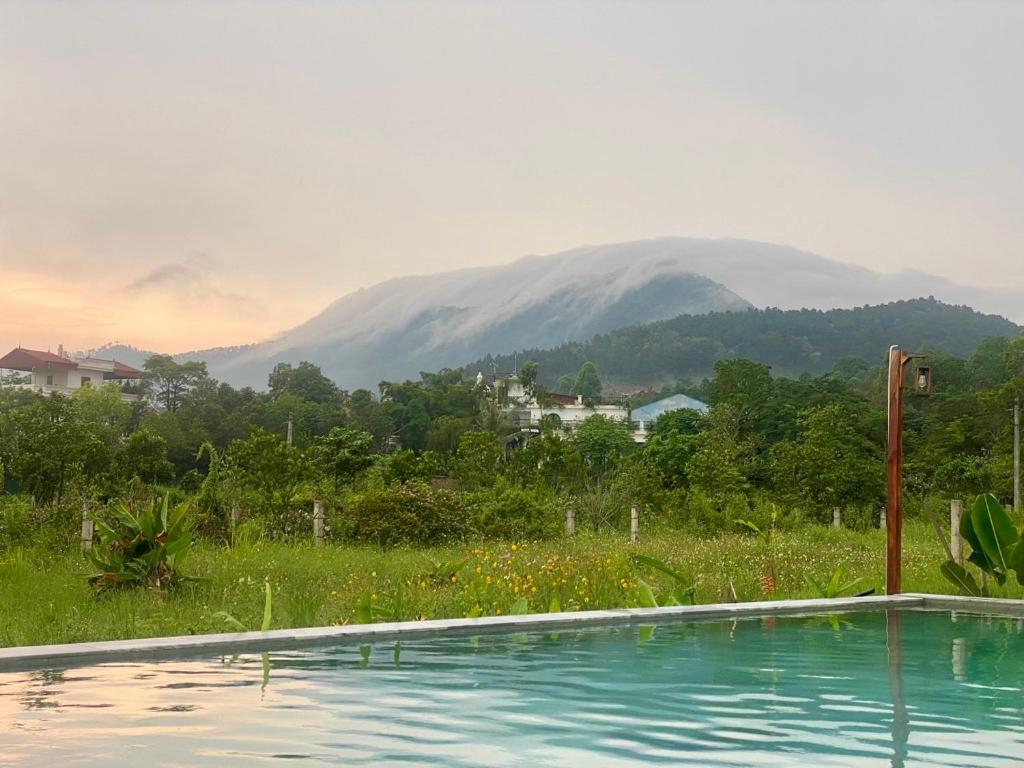 a swimming pool with a mountain in the background at Vườn của Nắng Bungalow in Sóc Sơn