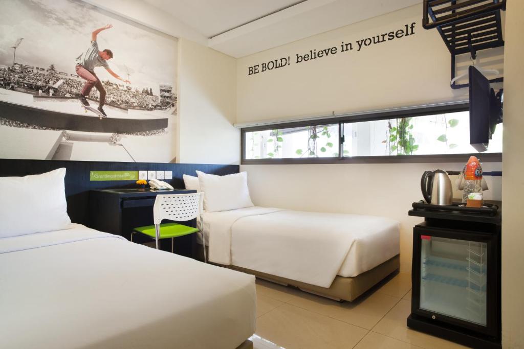 a hotel room with two beds and a tv at Grandmas Plus Hotel Seminyak in Seminyak