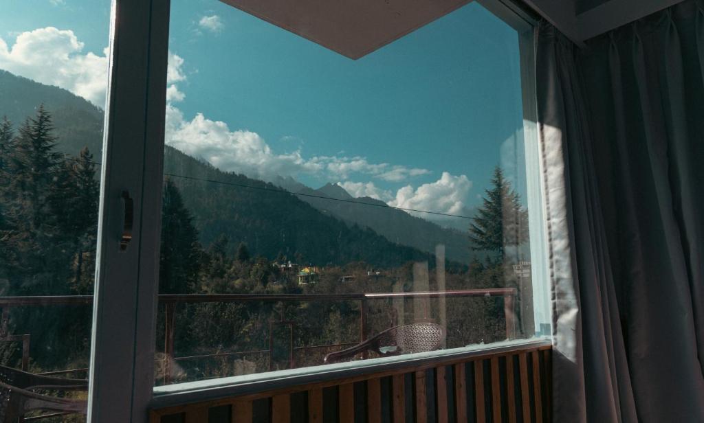een raam met uitzicht op een berg bij Himalayan View Hotel - Balcony & Mountain View Rooms in Manāli