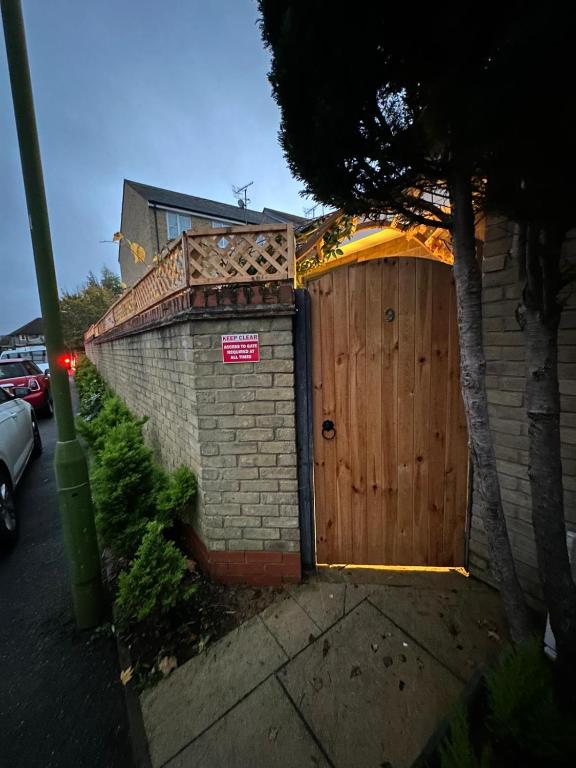a fence with a wooden gate with a sign on it at House in Watford