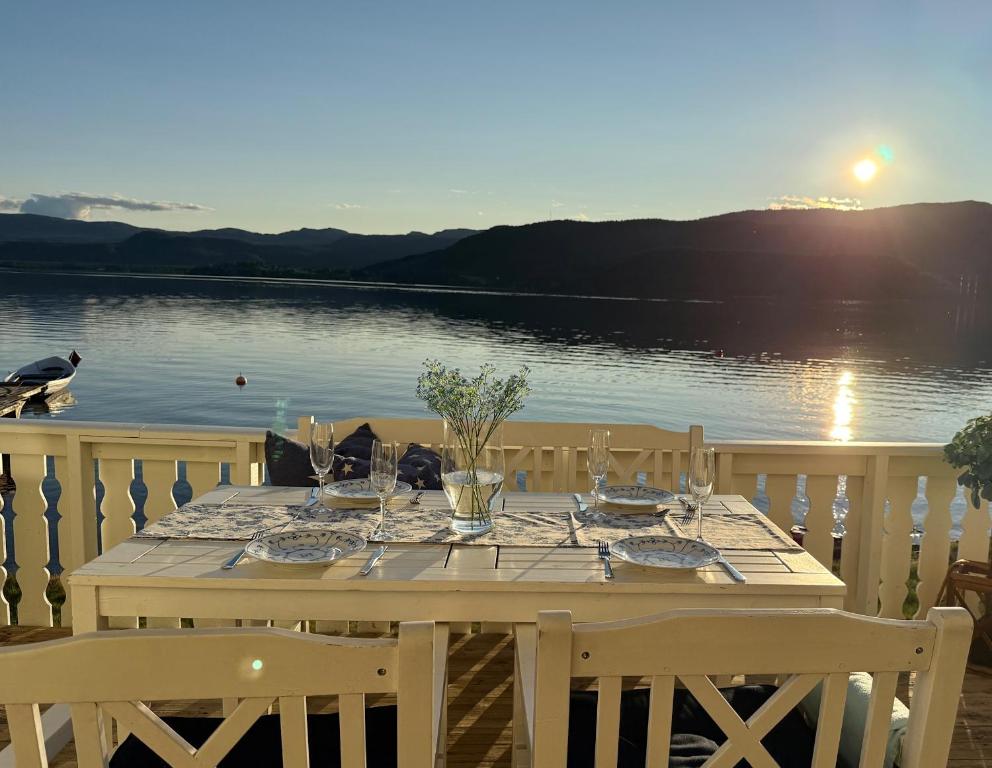 a table with plates and glasses on top of a lake at Feriehus ved Nisser med egen strand, brygge, peis og robåt til fri bruk in Kyrkjebygdi