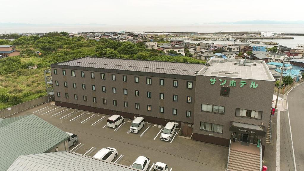 a building with cars parked in a parking lot at サンホテル大間 in Ōma