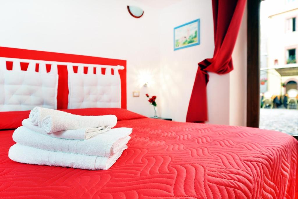 - une chambre avec un lit rouge et des serviettes dans l'établissement Ada's Guest house, à Bosa