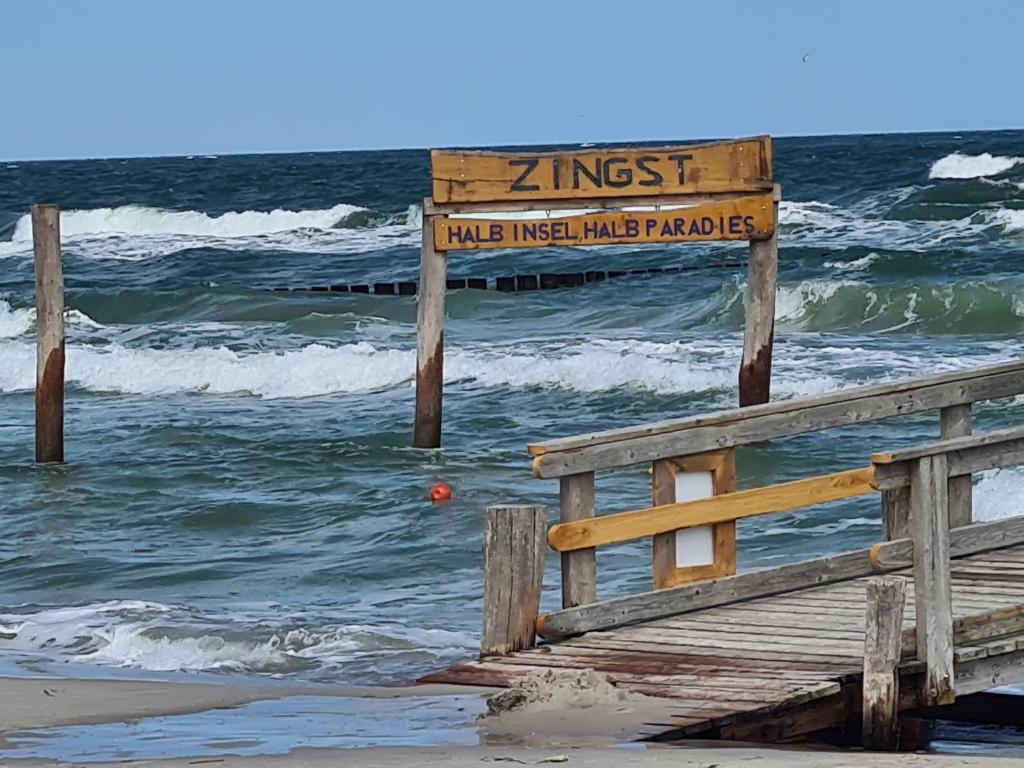 a wooden pier with a sign on the beach at Bungalow "Achtern" in Zingst
