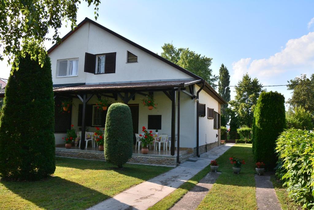 a white house with a porch and some bushes at Rózsa nyaralóház in Balatonboglár