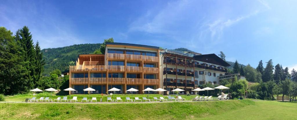 a building with chairs and umbrellas in front of it at Hotel Ansitz Haidenhof in Lienz