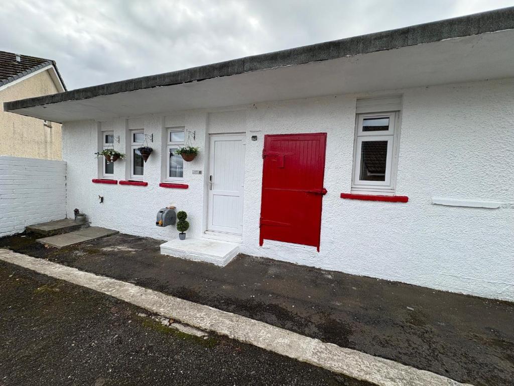 un edificio blanco con puerta roja y ventanas en Muirside Cottage, en Stirling
