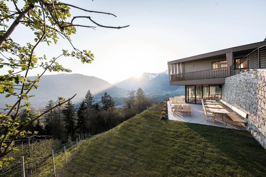 a house on a hill with mountains in the background at Florerhof in Schenna