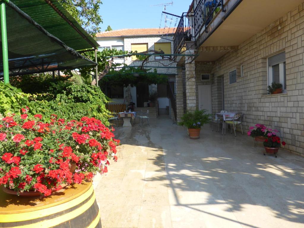 a patio with red flowers in a pot next to a building at Rooms Vilena in Medulin