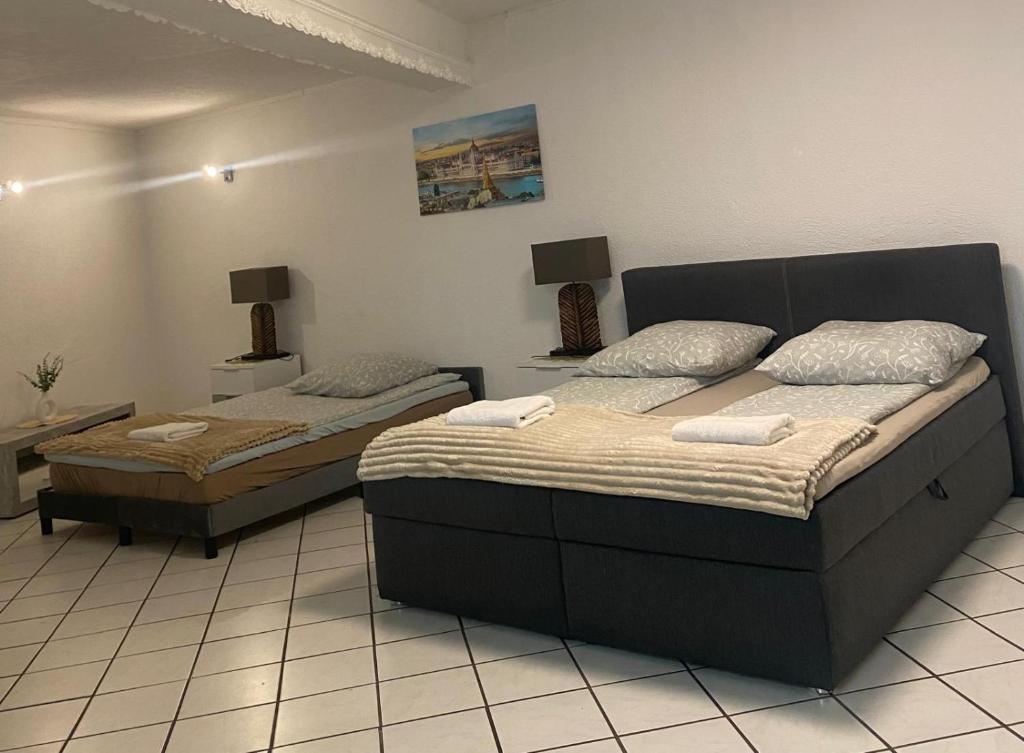 two beds in a room with two tables and lamps at Gästehaus Saarbrücken in Saarbrücken