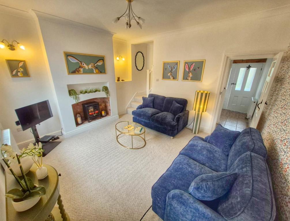 a living room with blue couches and a fireplace at Abbies Place in New Mills