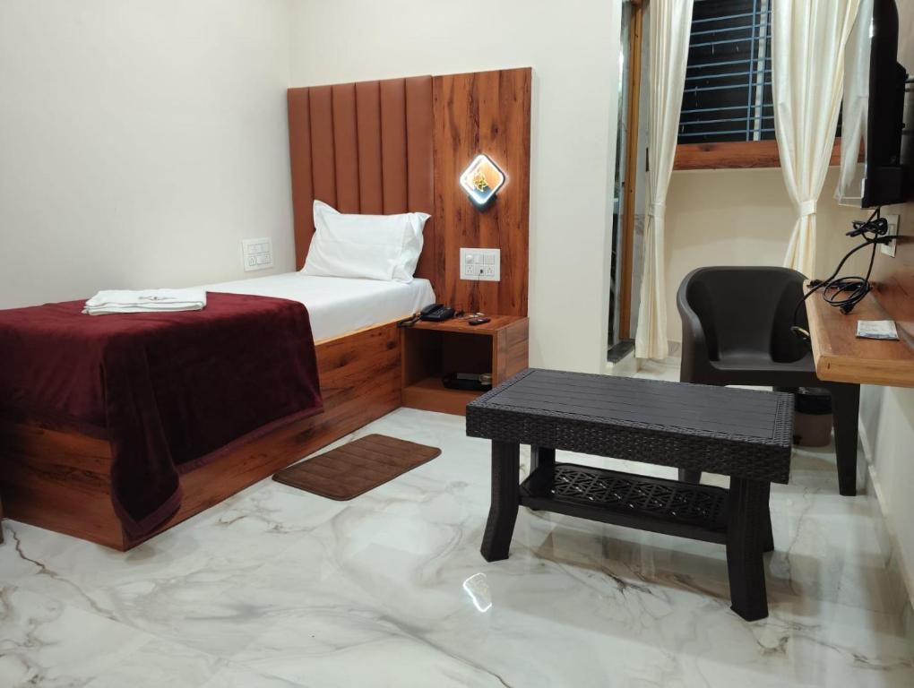 a bedroom with a bed and a table and a chair at Nandi residency in Dhārwād