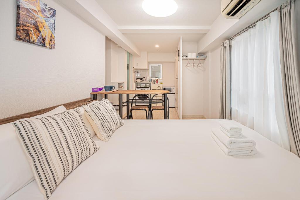 un letto bianco in una stanza con tavolo di Japan House Shirokane a Tokyo