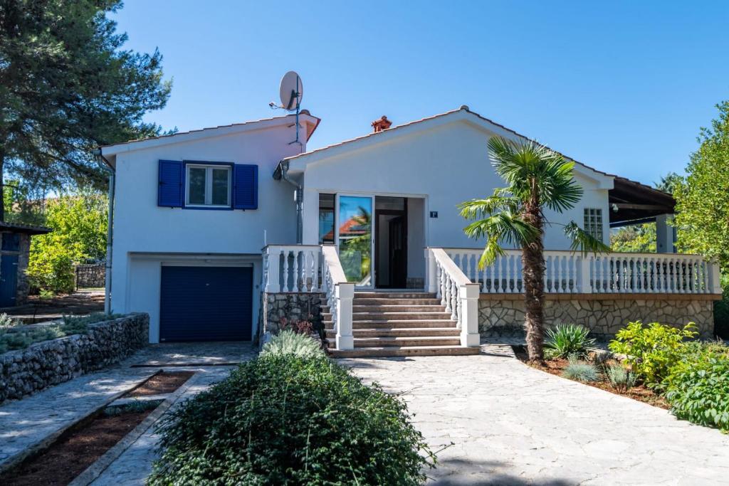 a white house with a palm tree at House Bianca with garden in Malinska
