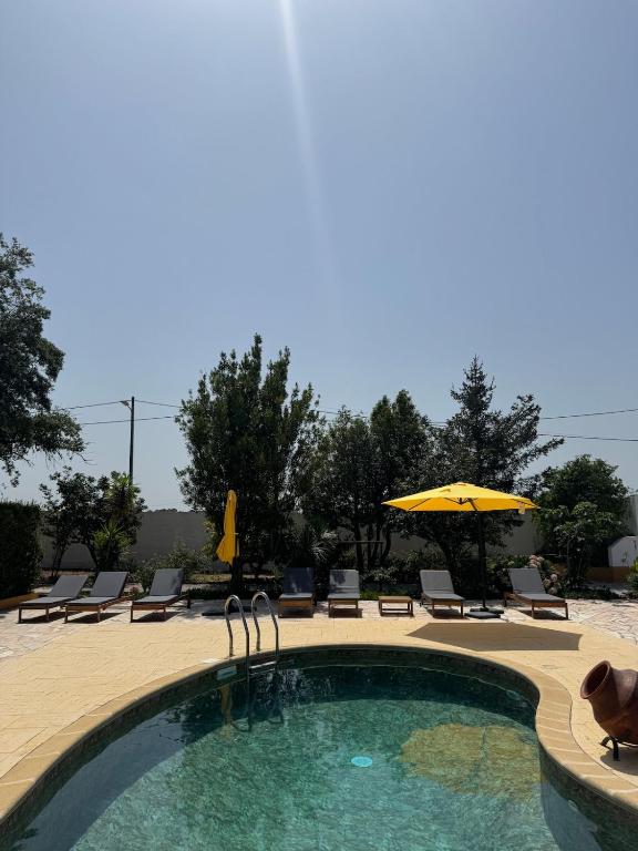 a swimming pool with chairs and an umbrella at Casa dos Sobreiros in Palmela