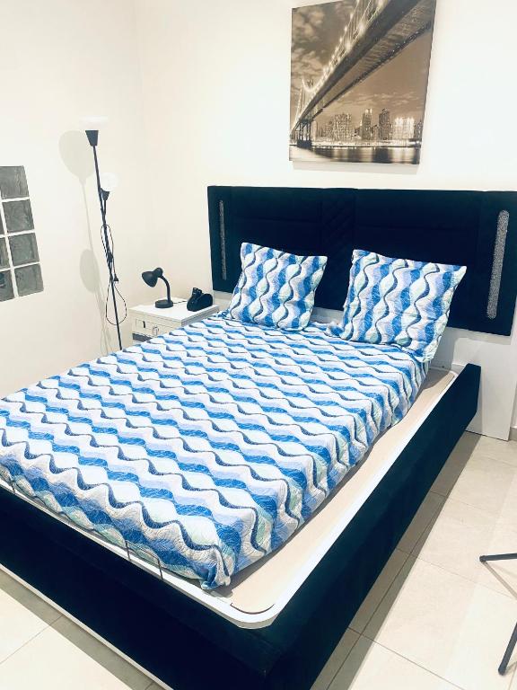 - un lit avec une couette et des oreillers bleus et blancs dans l'établissement Logement Proche gare de Villiers le bel, 20 mins de Paris , Stade 2 France, Aéro CDG, Parc des expositions, Disneyland Paris,Futuroscope, Tour Eiffel, à Arnouville-lès-Gonesse