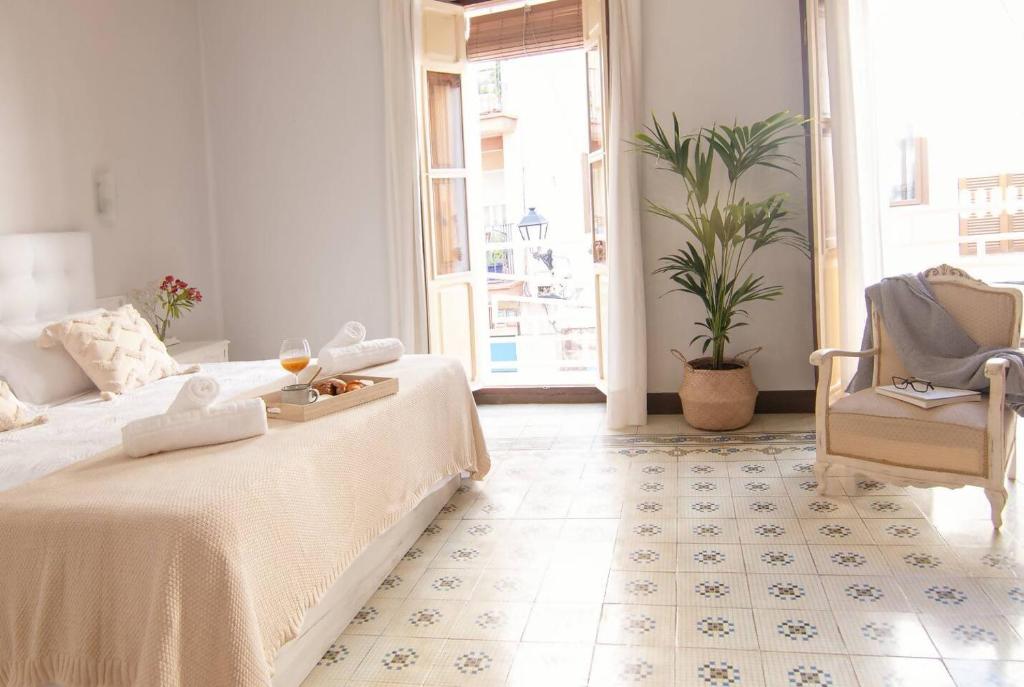 a white bedroom with a bed and a chair at Casa Casanova in Benissa