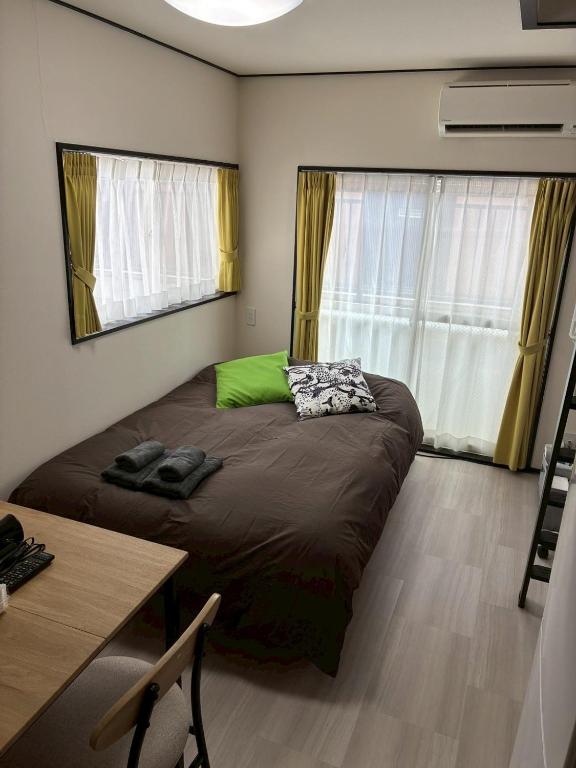 a bedroom with a bed with a green pillow and a desk at Corpo SKR by Tranova in Musashino