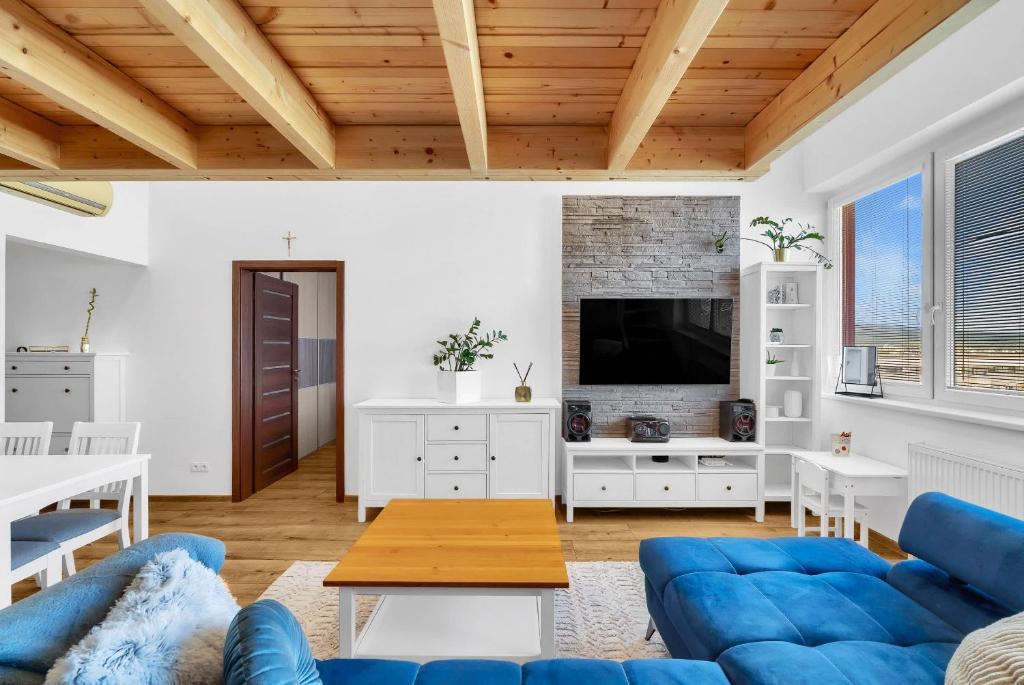 un salon avec un canapé bleu et une télévision dans l'établissement Sky View Family Apartment, à Trnávka