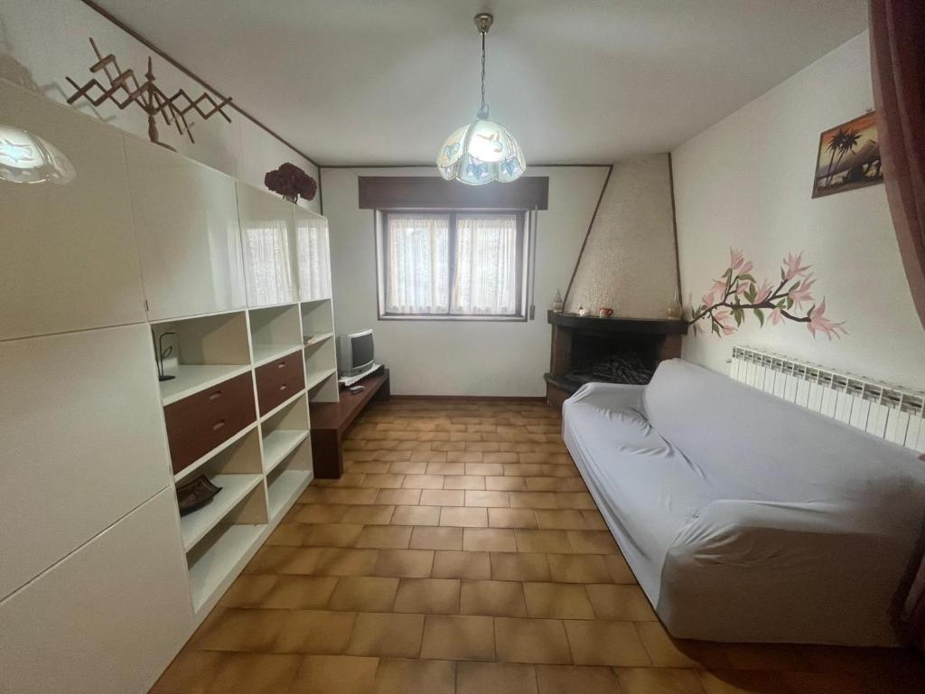 a living room with a white couch and a fireplace at Da Pino Affittacamere in Madonna di Fornelli