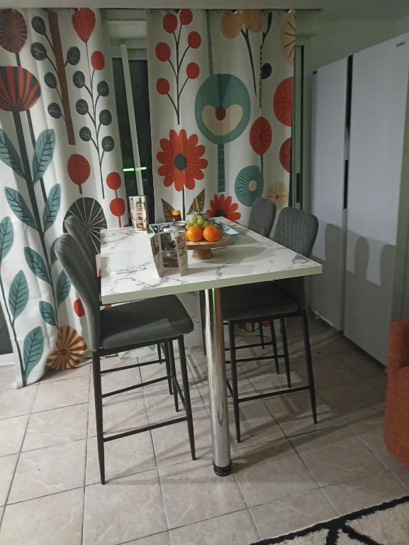 Le Cosy chic في Saint-Maurice-de-Beynost: طاولة عليها كراسي ووعاء من الفاكهة