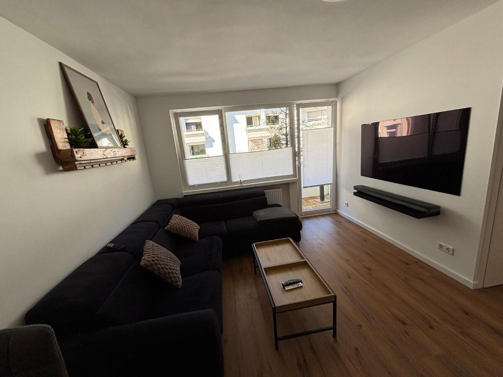 a living room with a black couch and a flat screen tv at NEU Design Loft nähe Medienhafen mit Balkon in Düsseldorf
