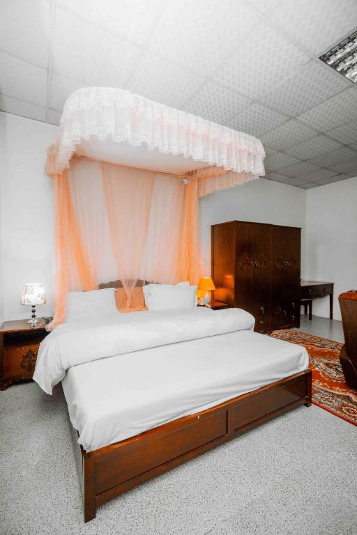 1 dormitorio con 1 cama grande con dosel de naranja en Mbeya Forest Hill Motel, en Mbeya