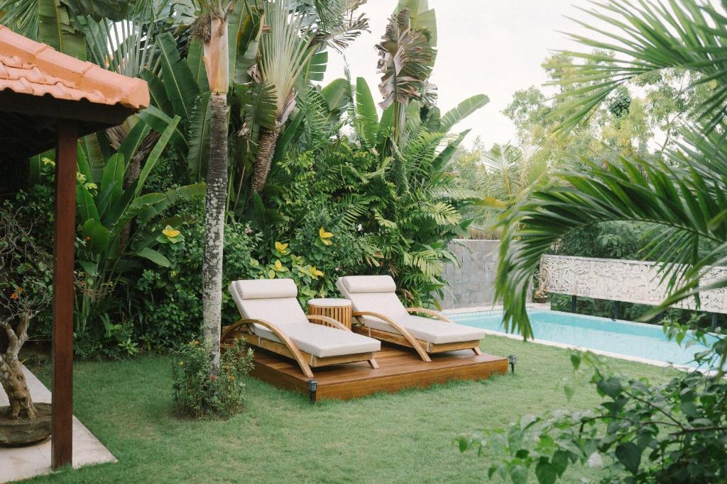 twee ligstoelen naast een zwembad bij Tropical Villa Asmara - 400sqm Garden Oasis with large Pool and Scenic Views in Uluwatu