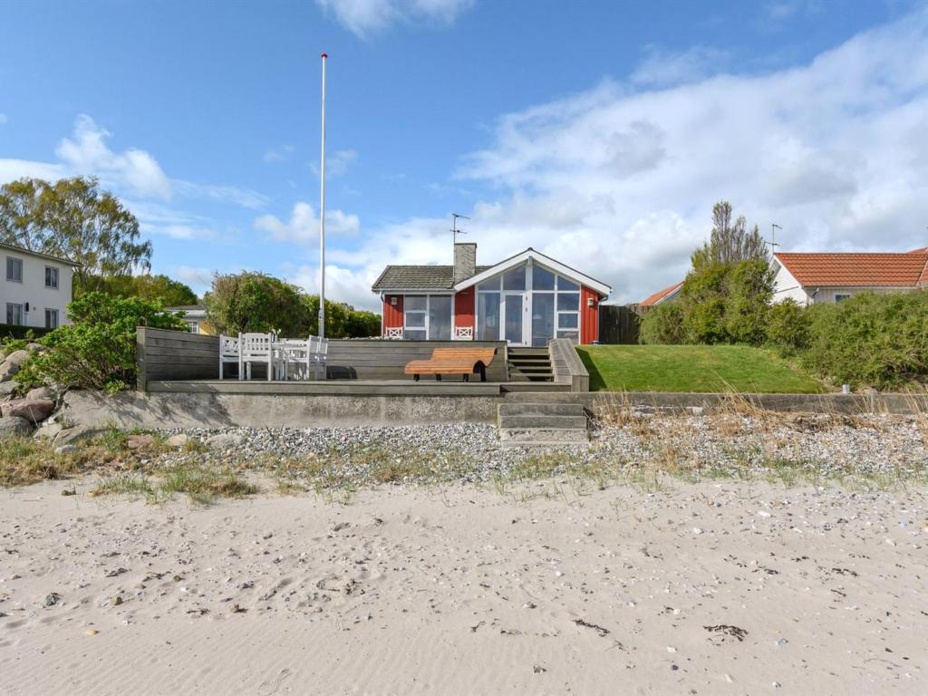 a red and white house with a bench on the beach at Holiday Home Keti - 5m from the sea by Interhome in Nyborg