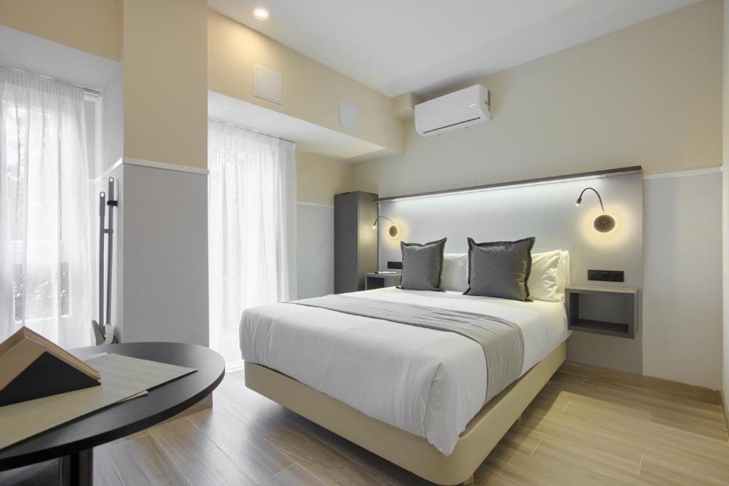 a bedroom with a large white bed and a table at Dobo Madrid CV93 in Madrid