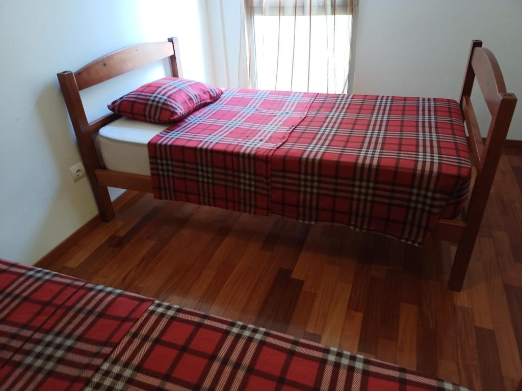 una camera con un letto con una coperta rossa a scacchi di Shared Room Funchal or Santa Cruz a Santa Cruz