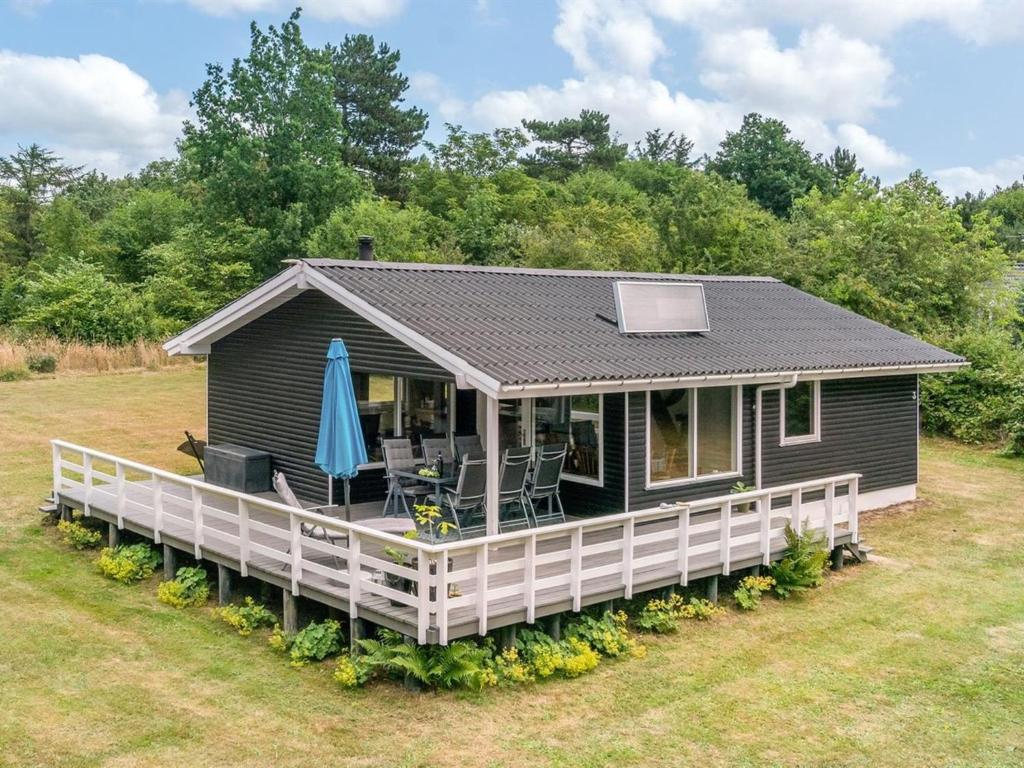 a small black house with a porch and an umbrella at Holiday Home Giertrud - 500m from the sea by Interhome in Humble