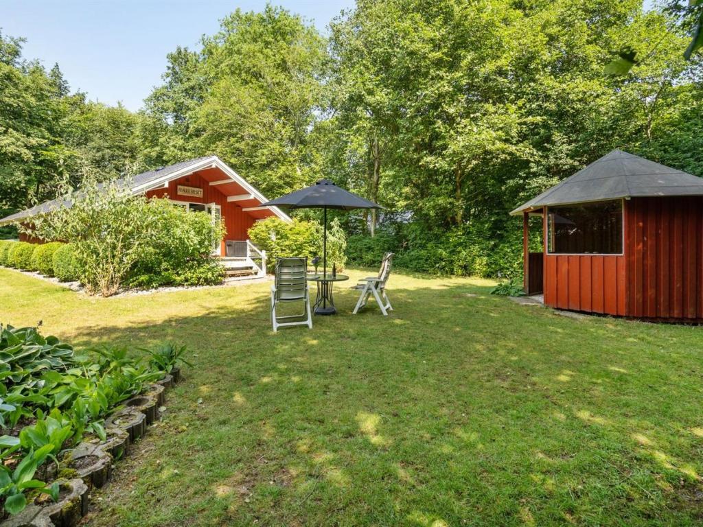 a yard with two chairs and an umbrella and a cabin at Holiday Home Rentje - 31km from the sea by Interhome in Toftlund