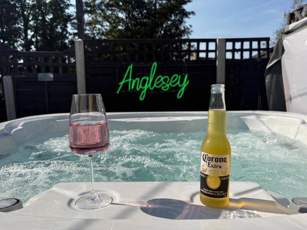 a glass of wine and a bottle of champagne in a hot tub at Gwens House - Traditional Cottage With Hot Tub in Brynsiencyn