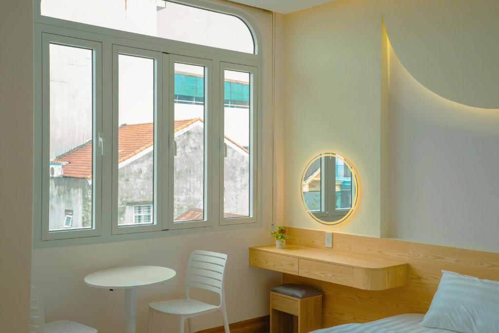 a bedroom with a bed and a table and windows at Tom's Homestay 2 in Hue