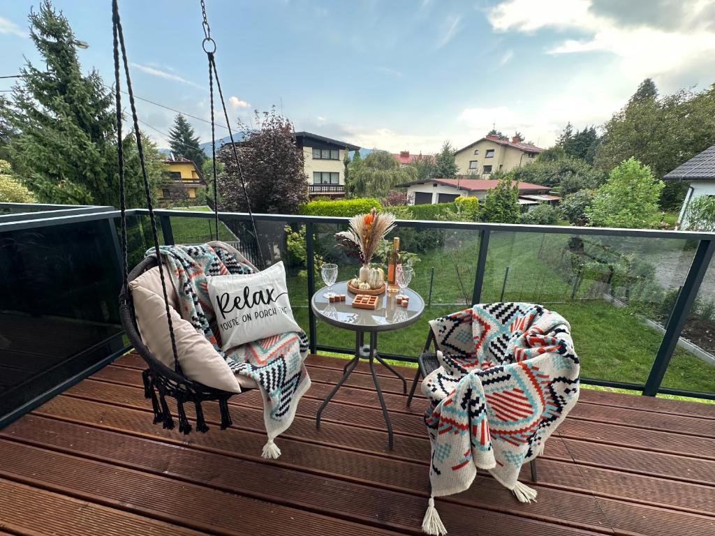 un porche con 2 sillas y una mesa en el balcón en Enduro Spot - Apartament pod Kozią Górą, en Bielsko-Biala