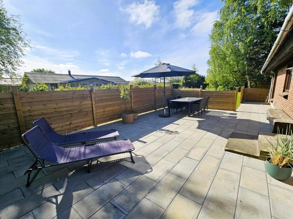 un patio con una mesa y una sombrilla en Holiday Home Gundis - 500m to the fjord by Interhome, en Tarm