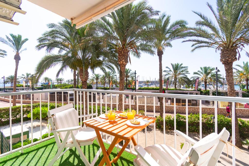 a balcony with a table and chairs and palm trees at Paraíso Frente al Mar con Piscina - By Aloha Palma in Águilas