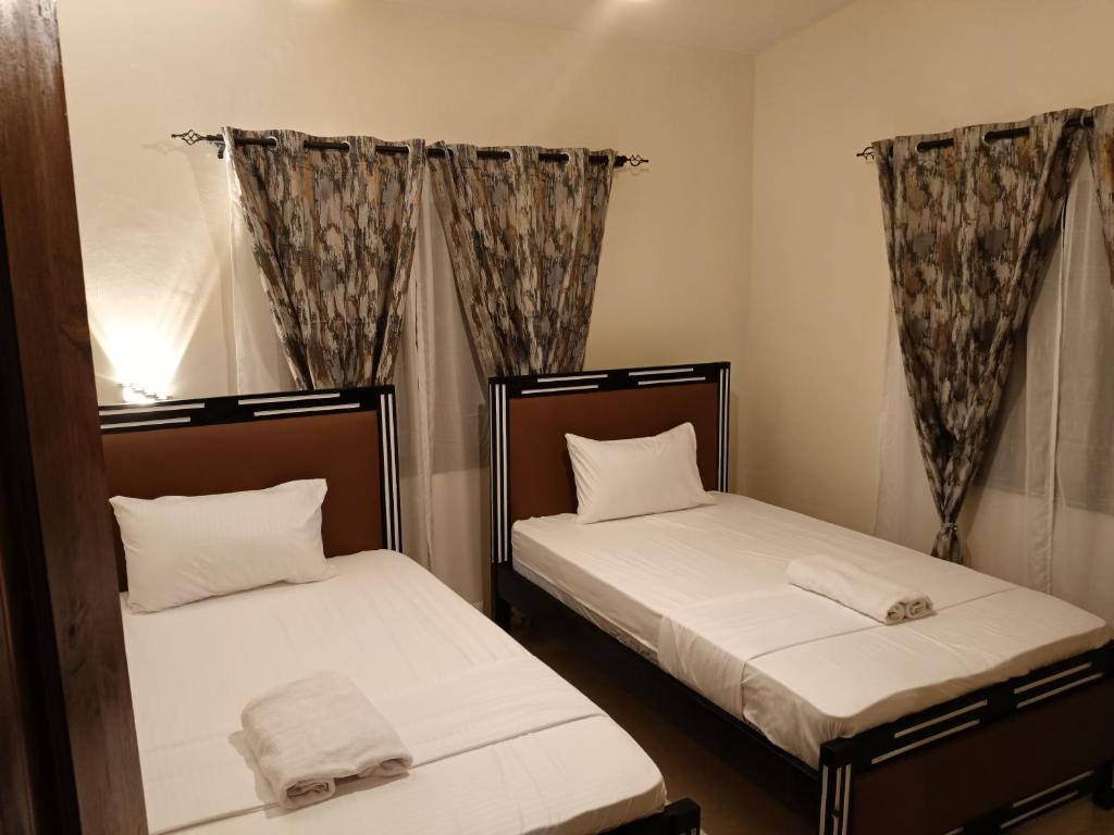 two beds in a small room with curtains at Modern Stand alone estate house in Mombasa
