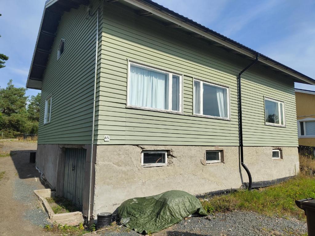 a green house with a green tarp in front of it at Omakotitalo rauhallisella alueella in Rauma