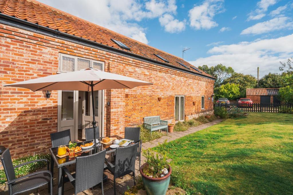 un tavolo con ombrellone in un cortile di Arthur's Cottage Visit England 4 star Cottage in Norfolk a Edingthorpe