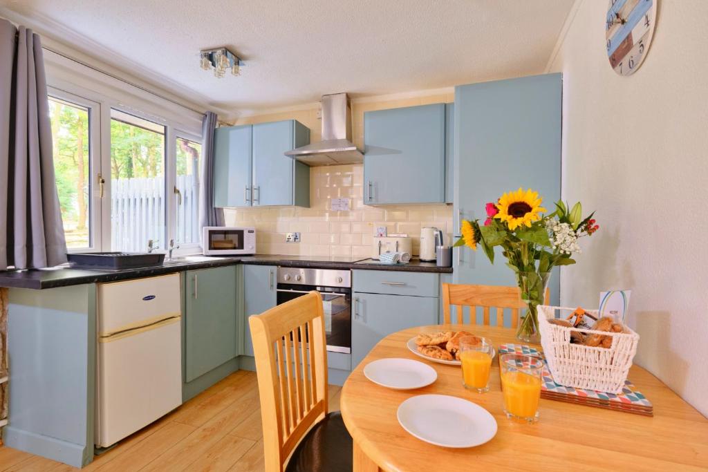 eine Küche mit einem Holztisch mit einer Blumenvase in der Unterkunft Finest Retreats - Joyful Cottage in Saint Erth