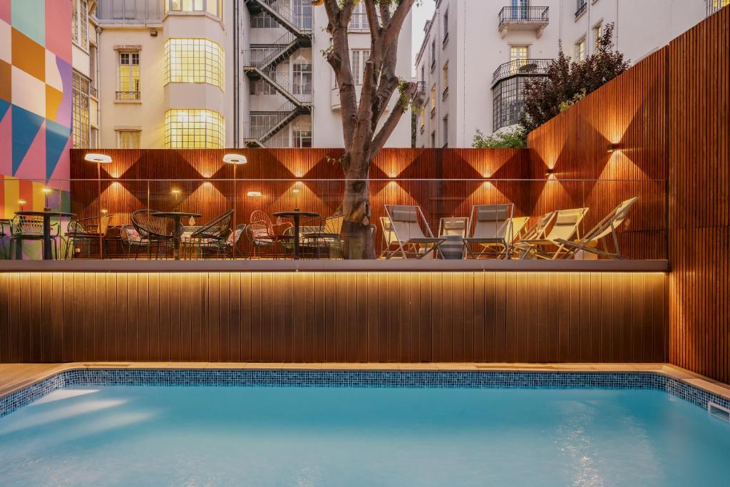 A small outdoor pool terrace enclosed by warm wood screens and surrounded by loungers.