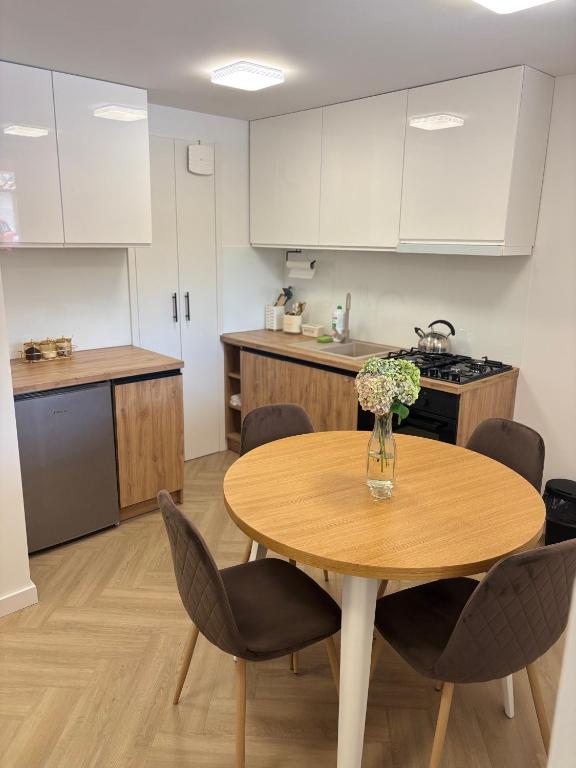 a kitchen with a wooden table with chairs and a vase of flowers at Apartament u Dyncyka in Krajno Pierwsze