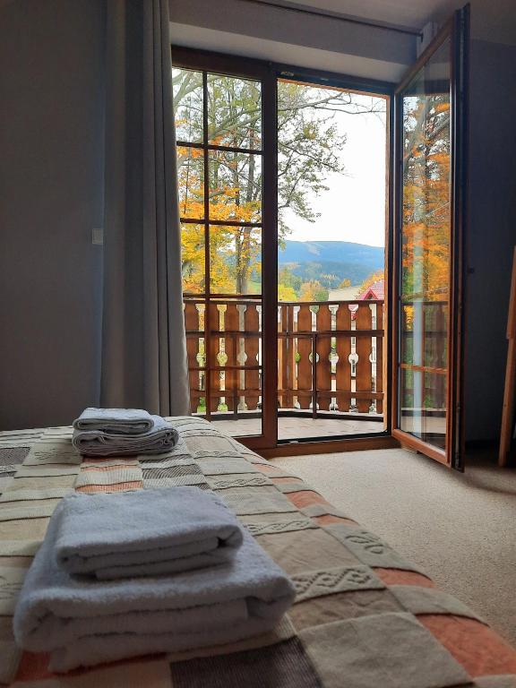 a room with a bed with towels on it with a balcony at Apartament 24 Karpacz in Karpacz