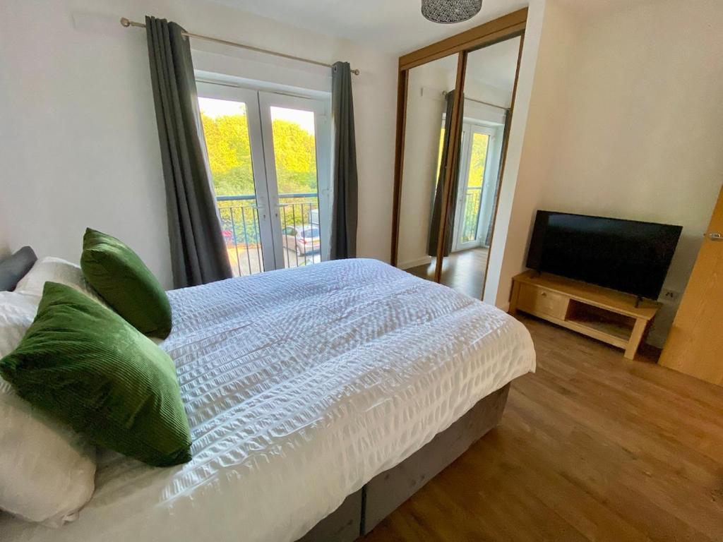a bedroom with a bed with green pillows and a television at 4 Bedroom House in Milton Keynes in Milton Keynes